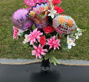 Mother’s Day bouquet of pink flowers and Best Mom balloons at a grave marker