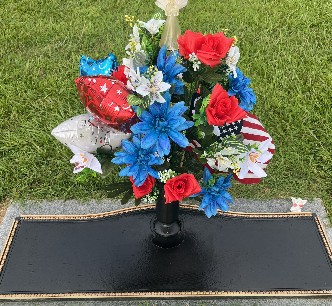 Patriotic red, white and blue flowers with star balloons at a grave marker